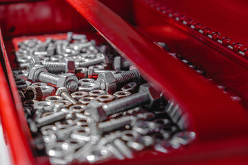 open red tool box on concrete, inside nuts and bolts. lock. light and shadow from the window. close up