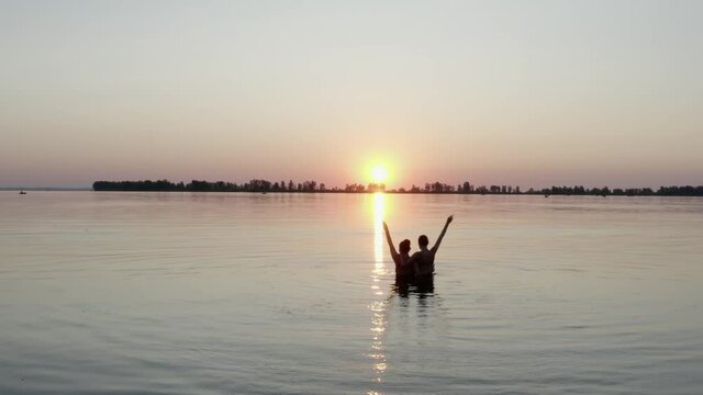 Two young girls are swimming in the river at sunrise. The calm expanse of water. No waves, dawn, Clear sky.