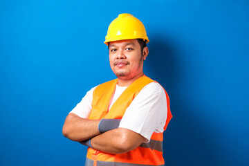 Potrait of fat asian worker wearing helmet and safety vest looking to camera crossed his hand with...
