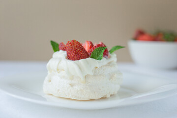 Mini Pavlova meringue cake with whipped cream, fresh strawberry and mint on the top. Delicious dessert. Selective focus.