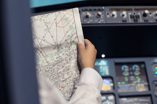 Young pilot in the aircraft in front of the dashboard. Pilot looks at the navigation map. Flight by commecial Airlines. Pre-flight preparation before the flight. Image with selestive focus. 