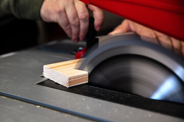 A man is sawing wood on a circular table saw