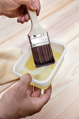 man is glazing a wooden table with a hair brush and oil
