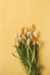 Colorful tulip flowers bouquet on yellow background. Flat lay, top view floral holiday celebration composition. Wedding, Valentine's Day, Mothers Day.