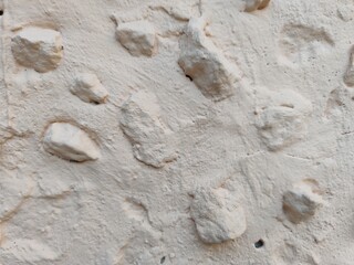 Plaster beige color, with large protruding elements in the form of stones.
