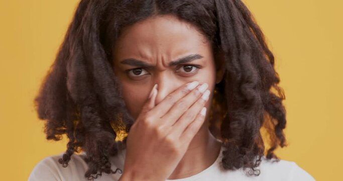Discontent black woman covering nose with hand