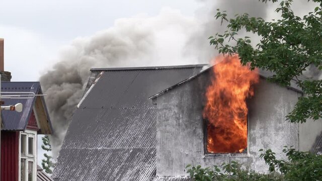 Flames from window and smoke from roof of burning house in Reykjavik Iceland