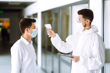 Obraz premium Disease control expert use an Infrared thermometer equipment to check the temperature on the forehead. Covid-19, quarantine or virus outbreak concept.