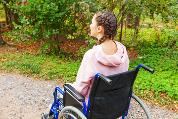 Young happy handicap woman in wheelchair on road in hospital park waiting for patient services....
