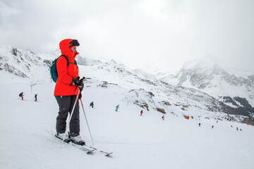 The skier stands on the slope before the descent and watches the training of skiers