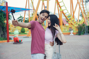 Happy Caucasian young couples take camera selfie photos together at theme park