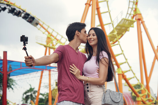 Happy Caucasian young couples take selfie photos together at theme park. kiss shot photo