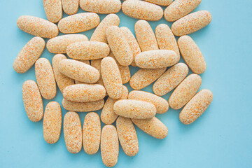 Health concept. Bright colored pills on blue background.  Handful of drugs, treatment. Vitamins and dietary supplements.
