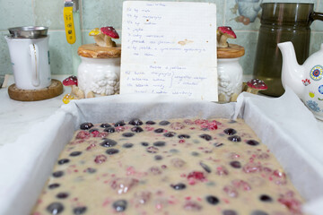 Preparation of cake with cherries and raspberries.