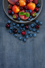 Fresh juicy berries and fruits on a plate close-up, top view