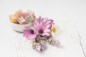 colorful Turkish delights and spring flowers on table with copy space