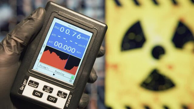 Scientist holds a Geiger counter to measure the microSieverts per hour of radiation at nuclear facility. Nuclear disaster and radiation fallout concepts. 