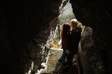 A pair of lovebirds, a man blonde and a girl with red hair stand on the bridge at the entrance to the cave. Portrait of a couple.