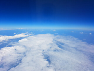 Fototapeta na wymiar View on the blue sky with clouds from airplane window