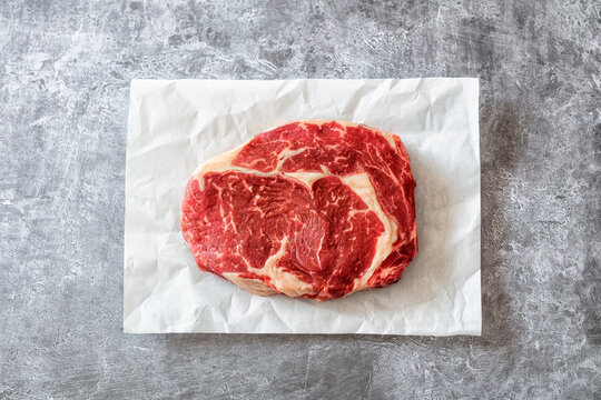 Entrecote (Ribeye) Steak auf Pergamentpapier mit grauem Untergrund