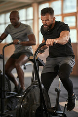 Fototapeta na wymiar Two men working out on stationary bikes in a gym