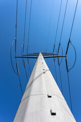 high voltage electric utility power lines against a bright blue sky