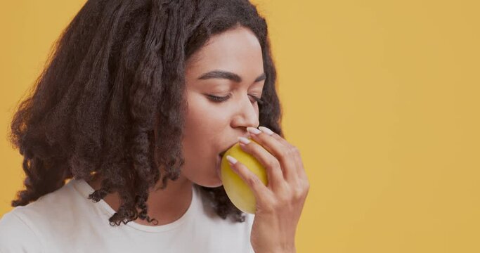 African american girl biting fresh apple and enjoying it