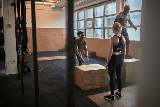 Diverse group of people doing box jumps at the gym