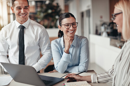 Three smiling coworkers talking together in an office