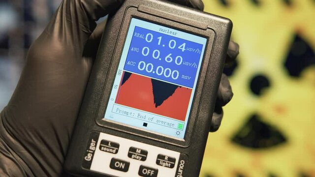 Scientist holds a Geiger counter to measure the microSieverts per hour of radiation at nuclear facility. Nuclear disaster and radiation fallout concepts. 