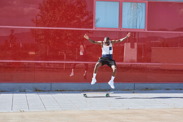 African American man jumps off a kick scooter. He is practicing on the street.