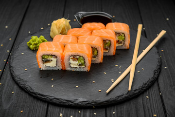 Sushi rolls with cheese philadelphia, salmon and tuna on a black background