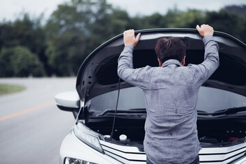 man looking by the broken down car. 