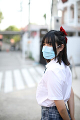 Asian school girl with mask in urban city on tree background