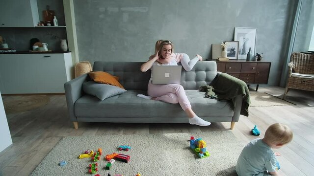 Young mum working at home and naughty blond kids playing