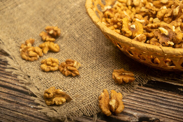 Peeled walnuts in a wicker basket and peeled walnuts scattered on a wooden table covered with rough-textured burlap. Healthy diet. Fitness diet. Close up.