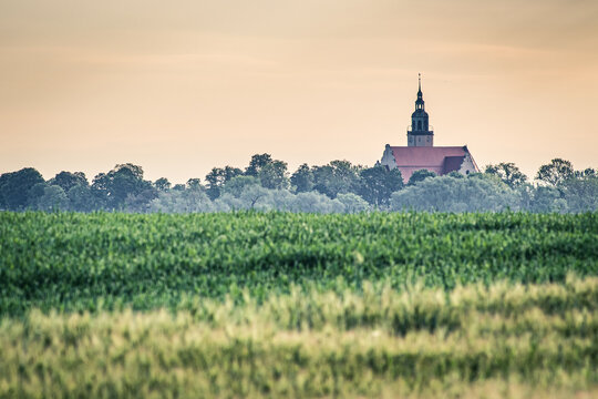 panorama z polami i kościołem wiejskim na wzgórzu
