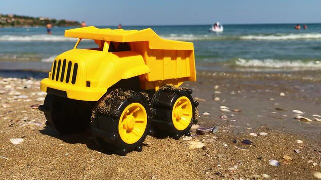 A yellow toy truck parked on the sand while tiny waves are approaching, Kavatsi, Sozopo, Bulgaria