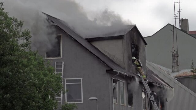 Firefighter on ladder and crane battle house fire in Reykjavik Iceland