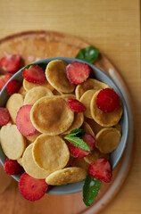 Trendy breakfast cereal pancakes. Little pancakes. Breakfast pancakes with strawberries. Pancakes close-up top view.