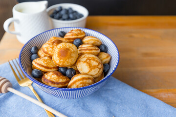 Mini cereal pancakes with berries on wooden table. Trendy food concept, Breakfast time for kids. Menu, recipe, top view or flat lay