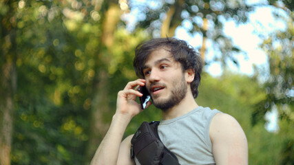 Young man with backpack talking on the phone in the forest.Technology concept