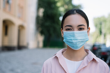 Portrait of pensive asian doctor wearing medical mask to protect from coronavirus infection looking at camera. Quarantine, virus, concept