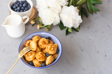Mini cereal pancakes with blueberries in a bowl on gray background. Trendy food concept, Breakfast time for kids. Menu, recipe, top view or flat lay
