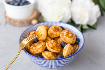 Mini cereal pancakes with blueberries in a bowl on gray background. Trendy food concept, Breakfast time for kids. Menu, recipe, top view or flat lay