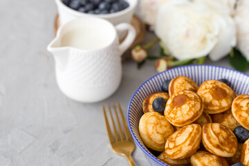 Mini cereal pancakes with blueberries in a bowl on gray background. Trendy food concept, Breakfast time for kids. Menu, recipe, top view or flat lay