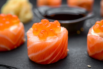 salmon sushi rolls on black background.