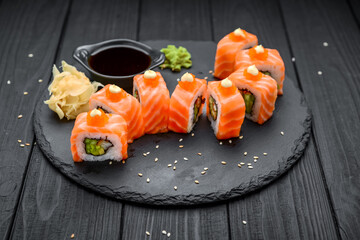 salmon sushi rolls on black background.