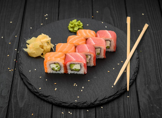 Sushi rolls with cheese philadelphia, salmon and tuna on a black background