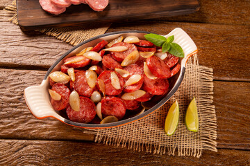 Smoked sausage with bread and onions on wood background. Snack appetizer calabrese sausage with onion.